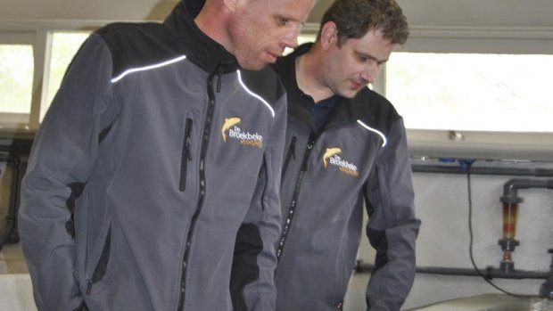 Martijn oude Kotte en Dennis Geerts (achter) bij de bak waar de duizend karpers zijn gestolen.